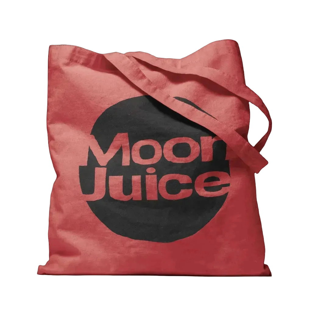 A red canvas tote bag with a large black circular graphic on the front featuring the text 'Moon Juice' in red, shown against a plain white background.