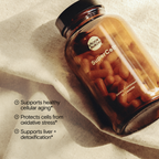 An amber glass bottle of Moon Juice SuperCell dietary supplement capsules, placed diagonally on a textured beige fabric background with soft shadows. White text on the left lists product benefits.